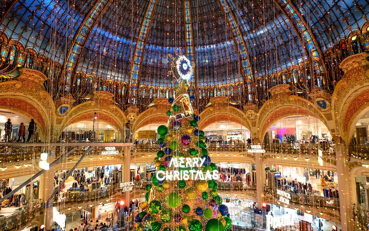 The Champs-Élysées glowing with sparkling Christmas lights leading to the Arc de Triomphe.