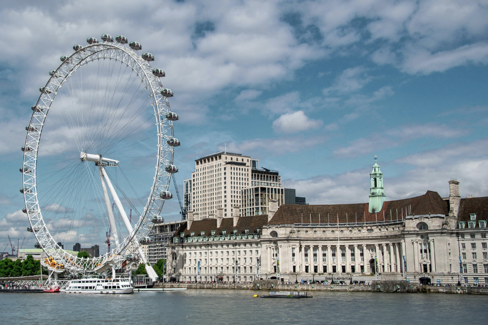 The London Eye rising above the River Thames with the city skyline in soft daylight.