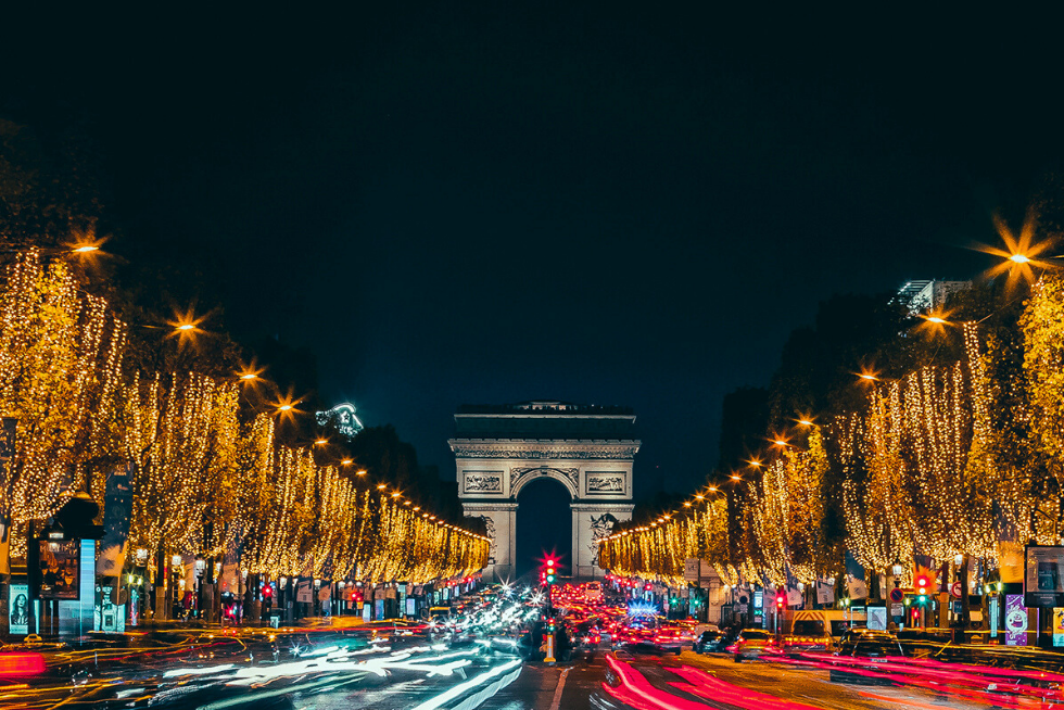 The Arc de Triomphe stands proudly at the end of the Champs-Élysées, illuminated by festive Christmas lights.